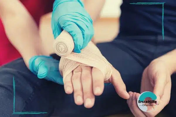 Erste-Hilfe-Kurs: Handverband-Anlage mit türkisen Handschuhen.