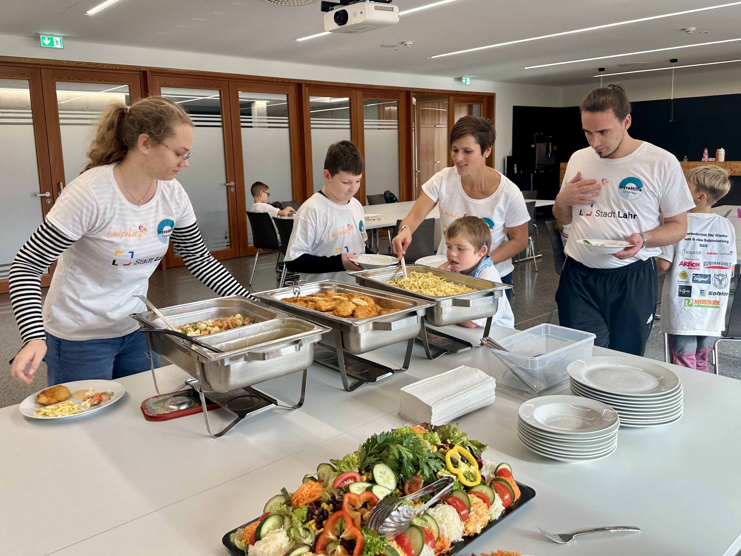 Buffet mit warmen Speisen und frischem Salat, während Teilnehmende des inklusiven Ferienprogramms Herbst 2025 in Lahr gemeinsam essen