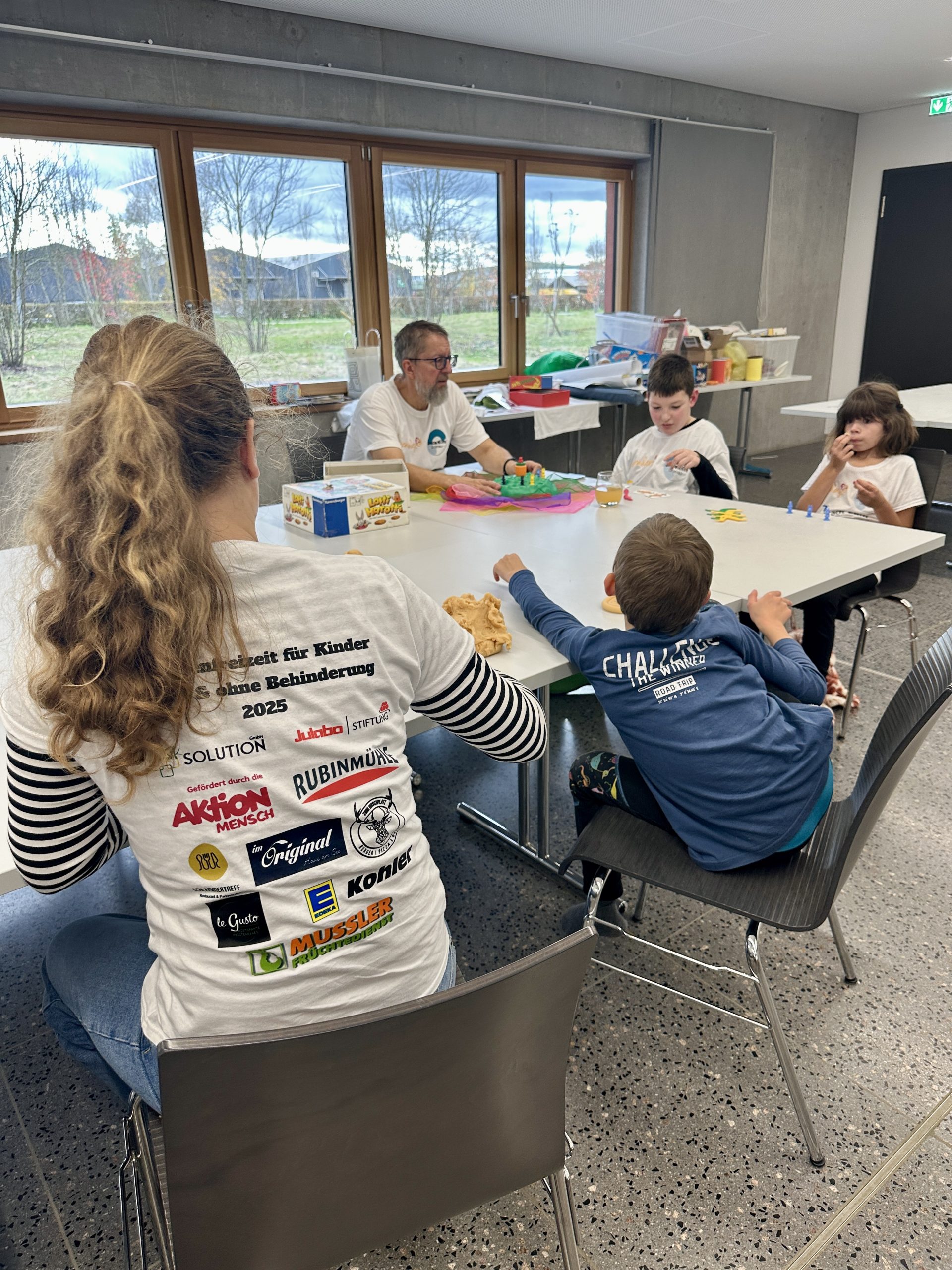 Kinder sitzen an einem Tisch und spielen sowie basteln gemeinsam beim inklusiven Ferienprogramm Herbst 2025 in Lahr