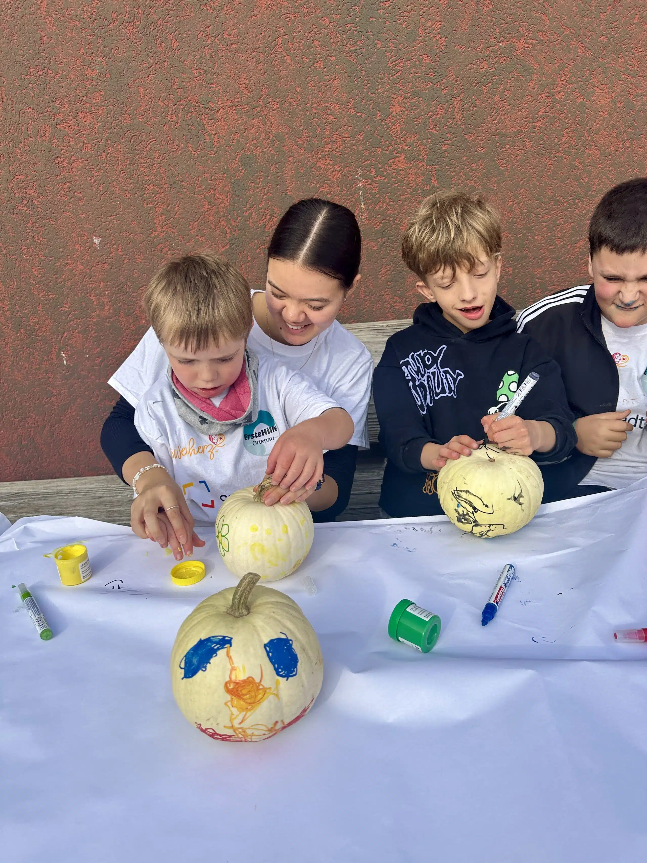 Kinder gestalten weiße Kürbisse mit bunten Farben und Stiften während einer Kreativaktion im inklusiven Ferienprogramm Herbst 2025