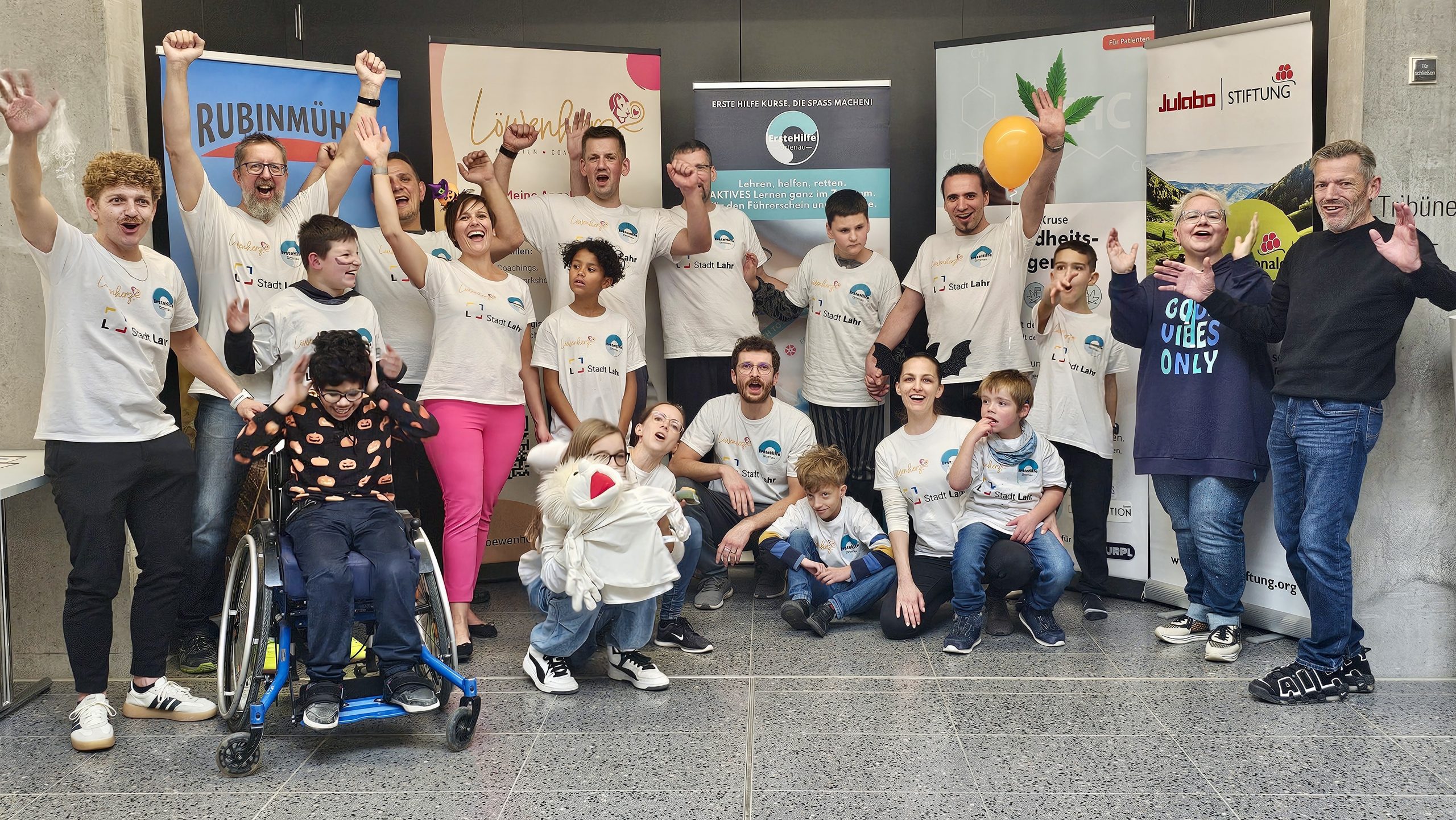 Teilnehmende des inklusiven Ferienprogramms Herbst 2025 stehen vor Sponsoren-Bannern und feiern gemeinsam den erfolgreichen Abschluss